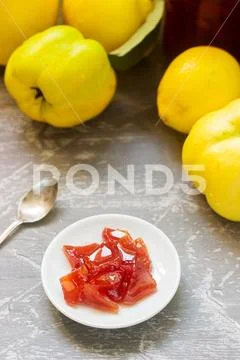 Quince jam on a white saucer, quince fruits and jars of jam on a gray backgro Stock Photos