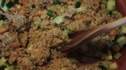 Quinoa and cucumber being fried in coconut oil in bronze brass nonstick pan Stock-Footage 247754294