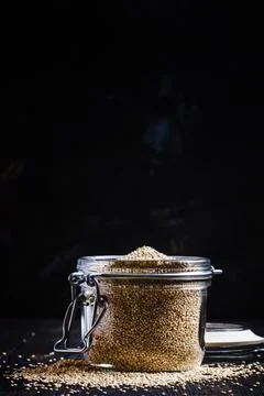 Quinoa in a jar on black background, selective focus Stock Photos