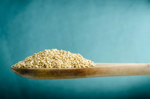 Quinoa in a spoon, close up, color background.. Stock Photos