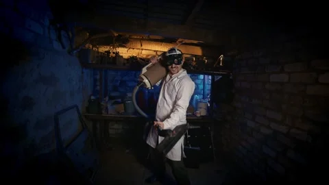 A quirky professor using an old vacuum in a cluttered garage. Video stock 329512069
