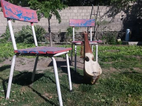 A rabab kept with two old chairs in a garden Stock Photos