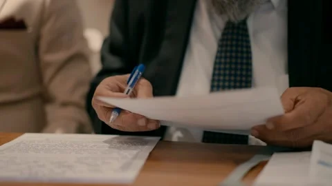 A rabbi reads a document while sitting at a table. Stock Footage 239156738