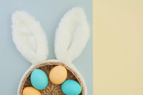 Rabbit ears as a symbol of easter and easter colored eggs in a basket on a two Fotos Stock