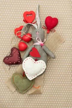 Rabbit handmade with red and white hearts lying on cardboard background in white Stock Photos