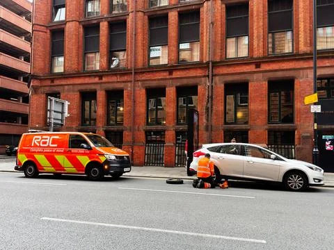 RAC roadside assistance worker changing a flat tyre on a silver car outside.. Stock Photos