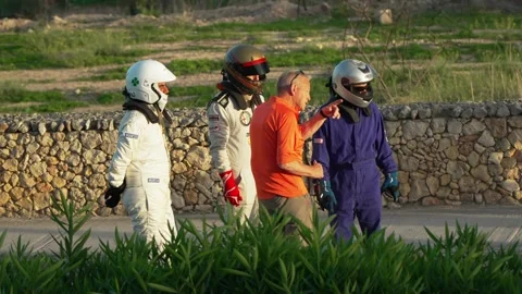 Race drivers with marshal post accident real time mid shot at Malta Classic Stock Footage 324934930