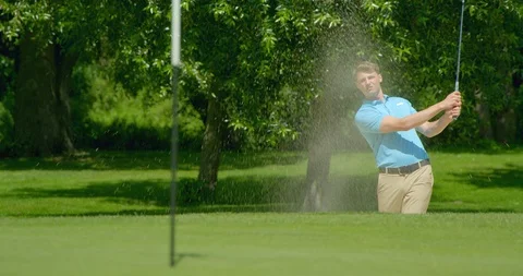 Rach focus on a golfer hitting sand trap / bunker shot to green. 库存影片 112019245