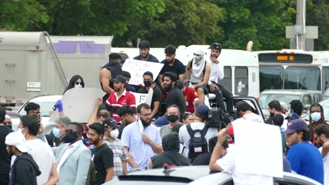 Racial protest during light rain after police shooting with men atop vehicle Video stock 133975483