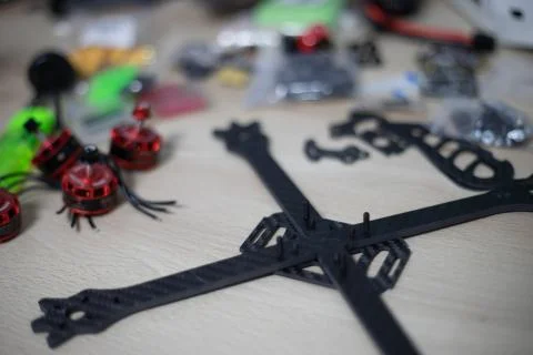 Racing drone frame being mounted on wooden table with blurred tools on backgr Foto stock