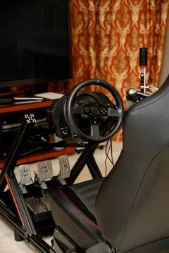 Racing simulator setup with steering wheel and pedals in home environment Stock Photos