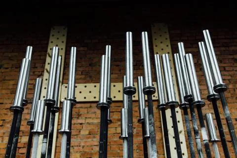 Rack of chromed vertical dumbbells on the PEGBOARD wall background and Benches Stock Photos