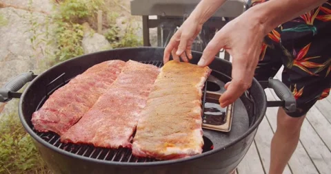 A rack of dry rubbed ribs being slow cooked and smoked on a kettle grill Stock-Footage 159608047