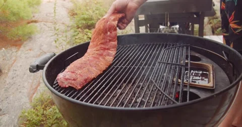 A rack of dry rubbed ribs being slow cooked and smoked on a kettle grill Stock-Footage 159608098