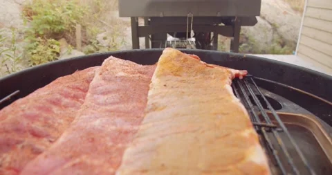 A rack of dry rubbed ribs being slow cooked and smoked on a kettle grill Stock-Footage 159608308