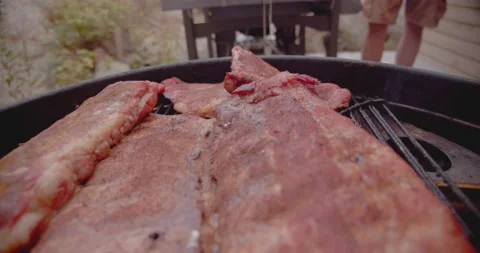 A rack of dry rubbed ribs being slow cooked and smoked on a kettle grill Stock-Footage 159608351