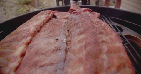 A rack of dry rubbed ribs being slow cooked and smoked on a kettle grill Stock-Footage 159608531