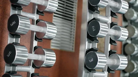 Rack with dumbbells in the gym. The movement of the camera along the rack with Video stock 173426134