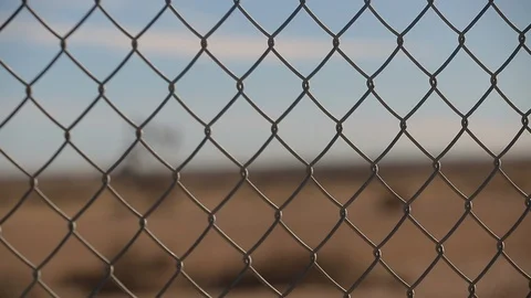 Rack focus of active oil derrick behind chain link fence Vídeo Stock 125685267