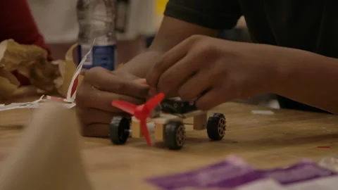 Rack focus to african american kid working in STEM on car Stock Footage 283489684