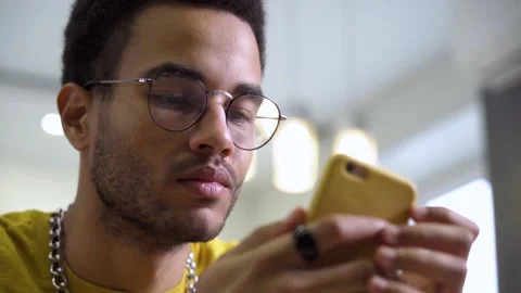 Rack Focus: An African young man uses a smartphone. Stock Footage 166690801