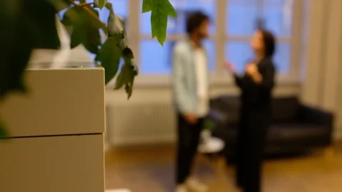 Rack focus and handheld shot of two young people talking in living room Stock Footage 120430268