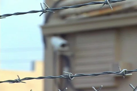 Rack Focus From A Barbed Wire Fence To Security Camera Stock Footage 140981