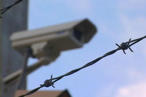 Rack Focus From A Barbed Wire Fence To Security Camera CU Video stock 140985