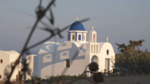 Rack focus from branches to iconic blue domed church on Santorini at magic hour Stock-Footage 239480836