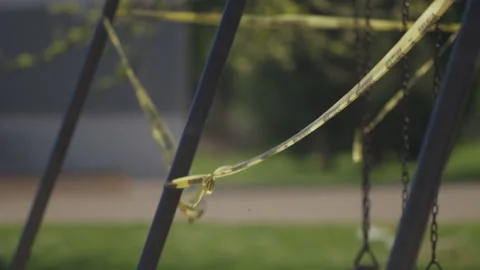 Rack focus of caution tape blowing in the wind at an empty playground Stock Footage 130389934