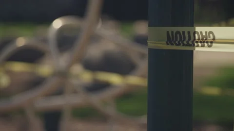 Rack focus on caution tape surrounding playground monkey bars during quarantine Video stock 130392793