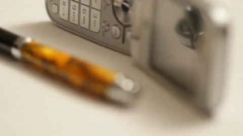 Rack focus from a cel phone to an elaborate pen Stock Footage 526517