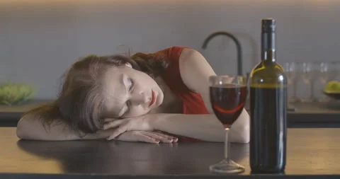 Rack focus changes from wine to drunk brunette woman sleeping on the table Stock Footage 139017760