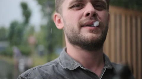 Rack focus close-up view of bearded man smoking cigarette. In nature, gentleman Stock Footage 160300186