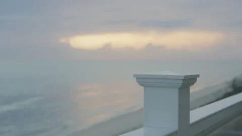 Rack focus close up white railing at beach home to stormy sunset Stock Footage 204106717