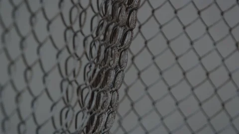 Rack focus on a curved chain link fence blowing in the wind Vídeo Stock 119041187