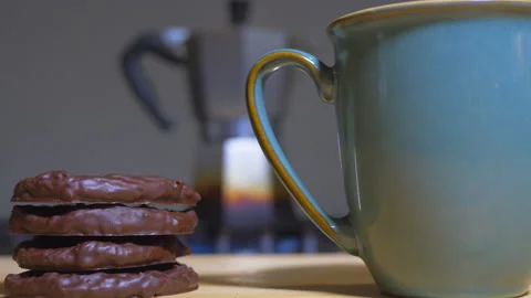 Rack focus / differential focus shot of a pot of coffee, a mug and biscuits. Video stock 134633625