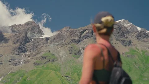 Rack Focus on Female Hiker Facing Towering Alpine Granite Peaks Under Clear Stock Footage 342027486