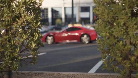 A rack focus (focus change) to a red Ferrari vehicle / car parked and some Stock Footage