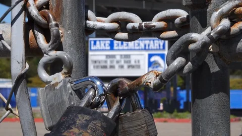 Rack focus of locked gate and sign of closed down school Stock Footage 126594673