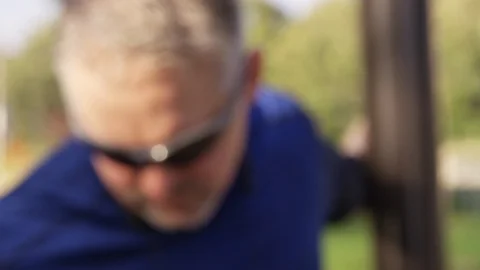 Rack focus to a man stretching his arms at an exercise park - slow motion - shot Stock Footage 123491034