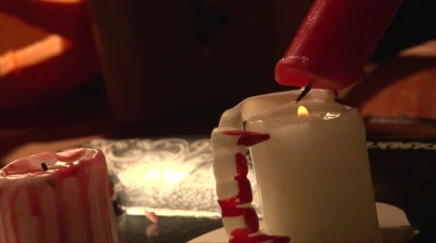 Rack focus melting red wax on white candle, vampire teeth Stock Footage
