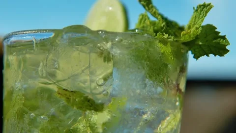Rack focus of mint sprigs as bubbles rise in mojito, shallow depth of field Stock Footage 253801453