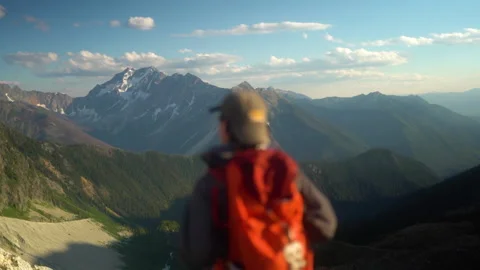 Rack focus from mountain landscape to caucasian man walking out to viewpoint Stock Footage 207610367