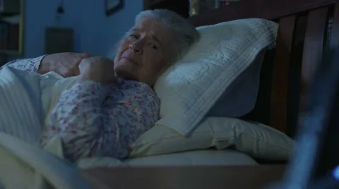 Rack focus from a phone to an elderly female woman in bed Stock Footage 67029983