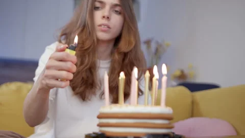 Rack focus pretty young brunette lighting candles on birthday cake in room while Stock Footage 248263149