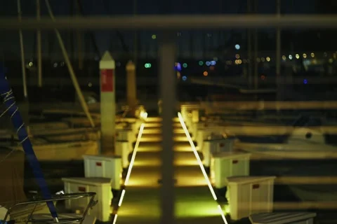 Rack Focus From Railing to Illuminated Marina Walkway at Night 動画素材 321714906