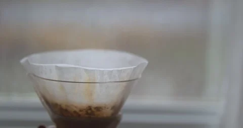 Rack Focus from a Rain Droplet Covered Window to a Steaming Chemex Coffee Filter Stock Footage 100095535