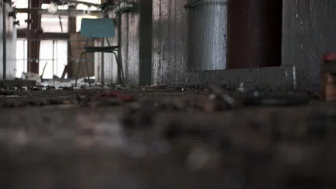 Rack focus rusty bolts lie on old, dirty floor in abandoned, broken factory Stock Footage 167554589