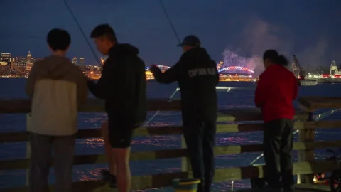 Rack Focus Shifts From Fireworks to Blurred Anglers at Night Stock Footage 341357538